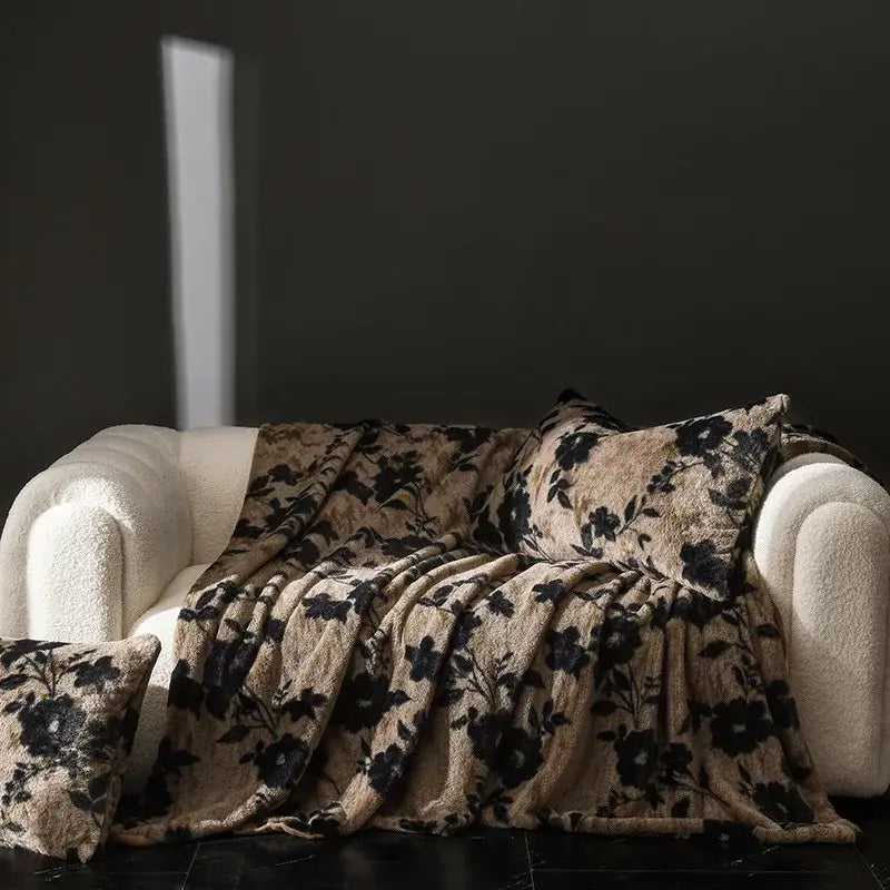 Beige and black floral patterned cosy faux rabbit plush throw blanket draped over cream sofa for living room decor