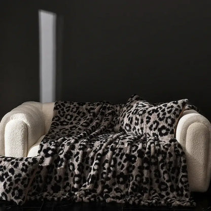 Cosybites cosy faux rabbit plush leopard print throw blanket in black and beige draped over cream sofa for living room decor