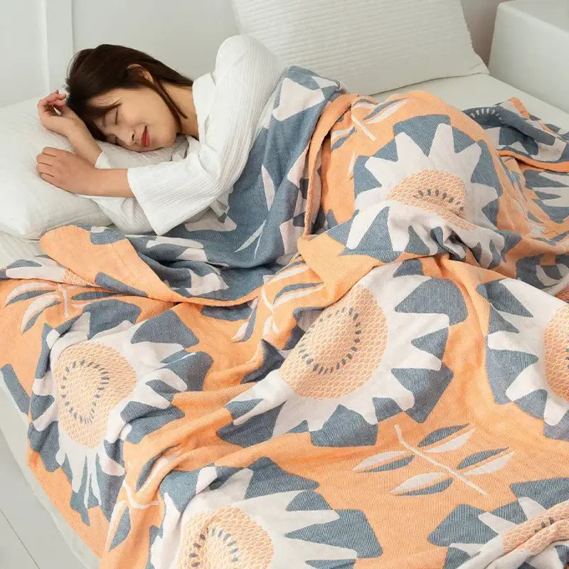 A cozy peach and blue sunflower-patterned cotton gauze boho throw with a soft textured weave for bedroom decorbites cotton gauze