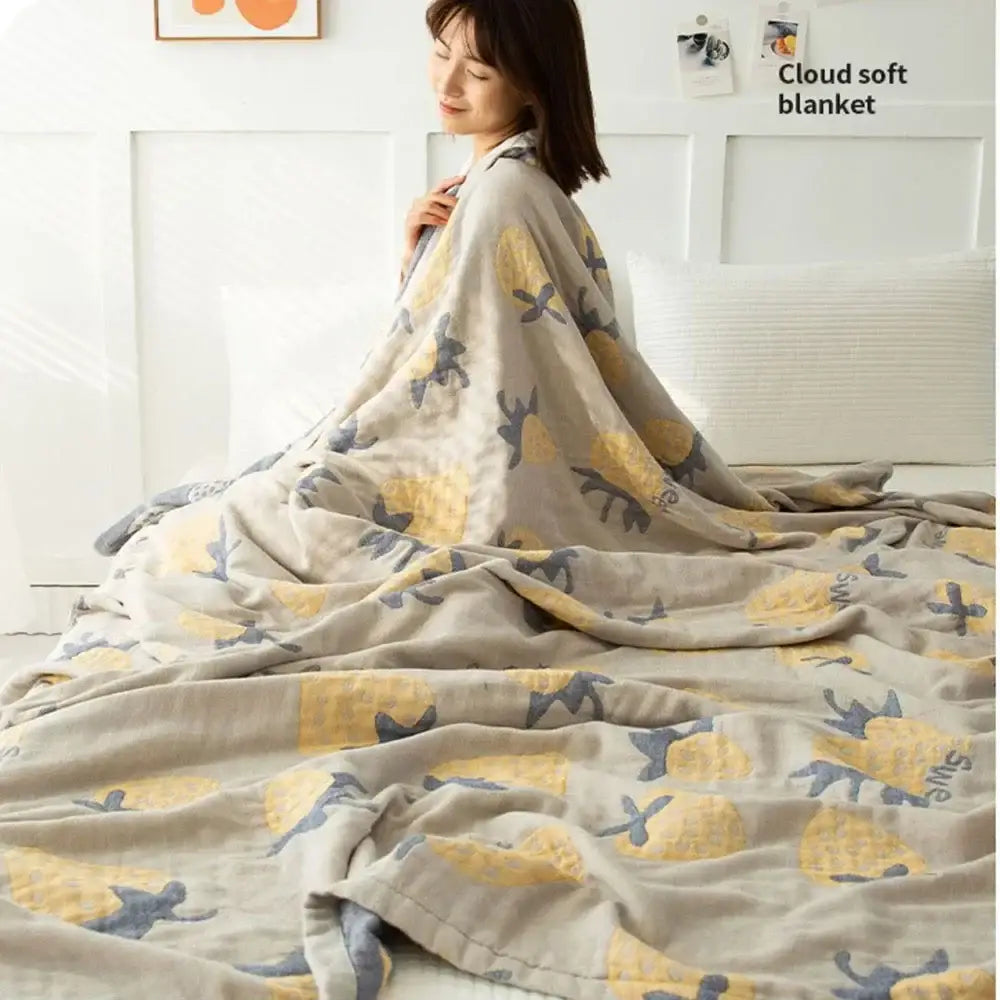 A cozy beige decorbites cotton gauze boho throw blanket with yellow pineapples and gray silhouettes for bedroom decor