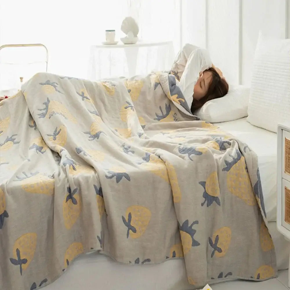 A soft light gray decorbites cotton gauze boho throw with yellow pineapples and dark blue birds pattern