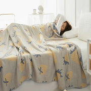 A soft light gray decorbites cotton gauze boho throw with yellow pineapples and dark blue birds pattern