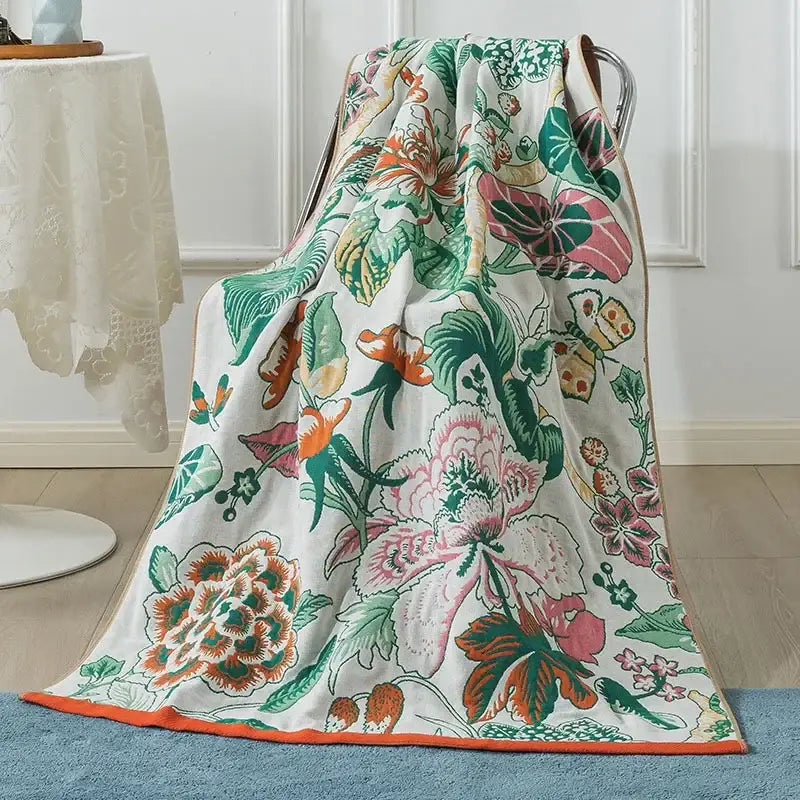 A decorbites cotton gauze peacock cream and orange bath towel with vibrant floral pattern and orange border