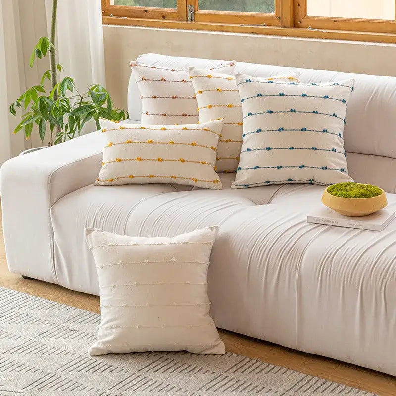 Cream-colored decorbites cotton stripe jacquard throw pillows with yellow and blue embroidered lines on white sofa