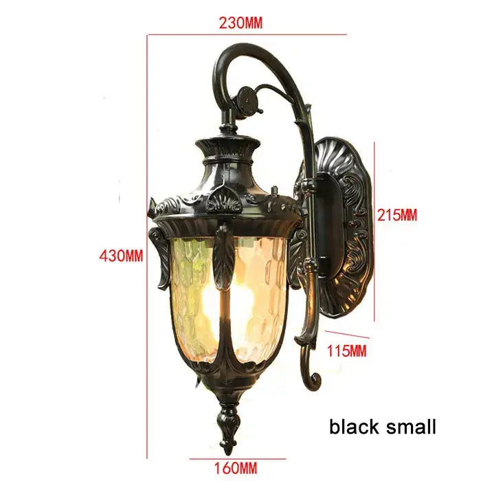Black wrought iron outdoor wall lantern with ornate metalwork and textured amber glass shade for outdoor wall use