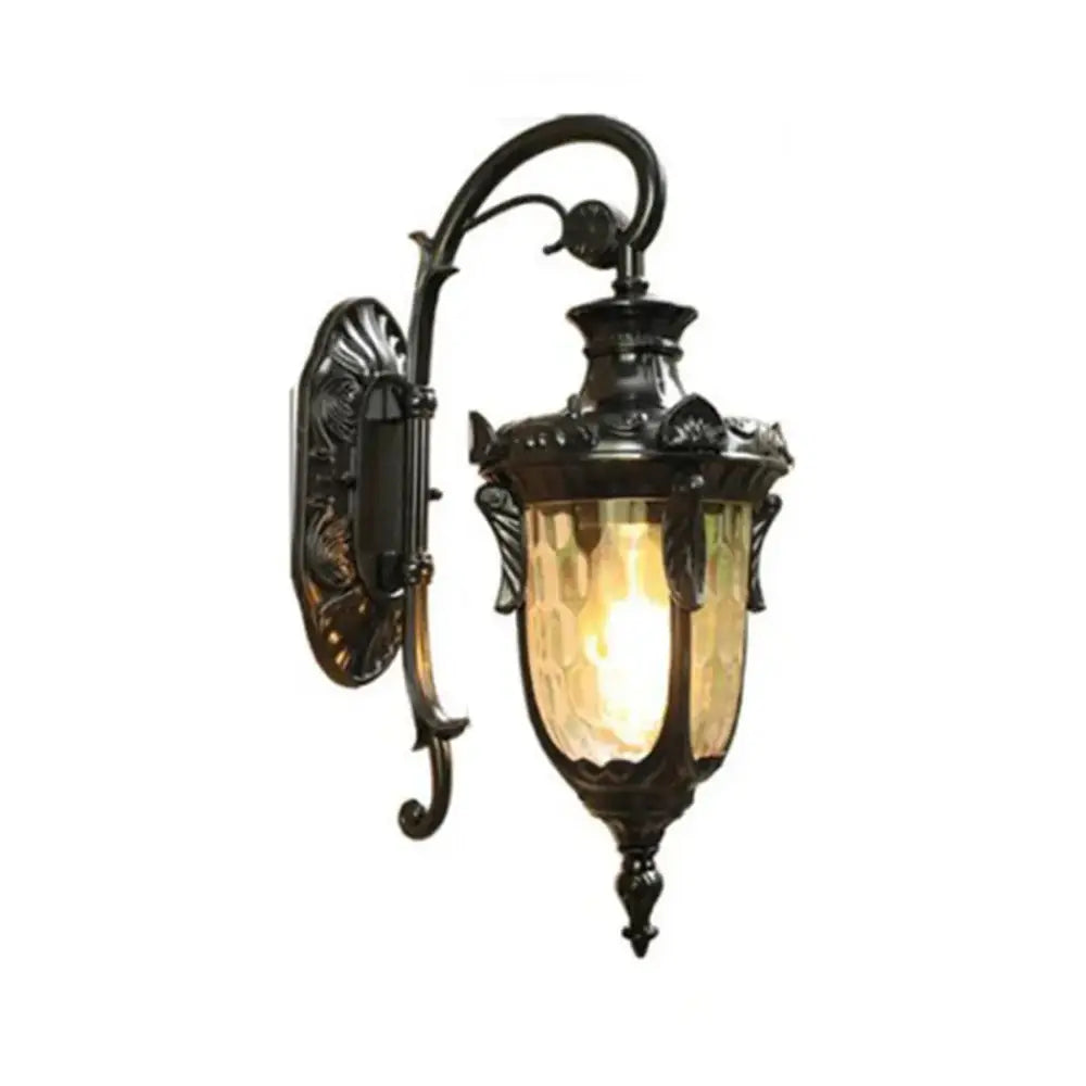 Country black wrought iron outdoor wall lantern with ornate scrollwork and textured amber glass shade for outdoor wall use