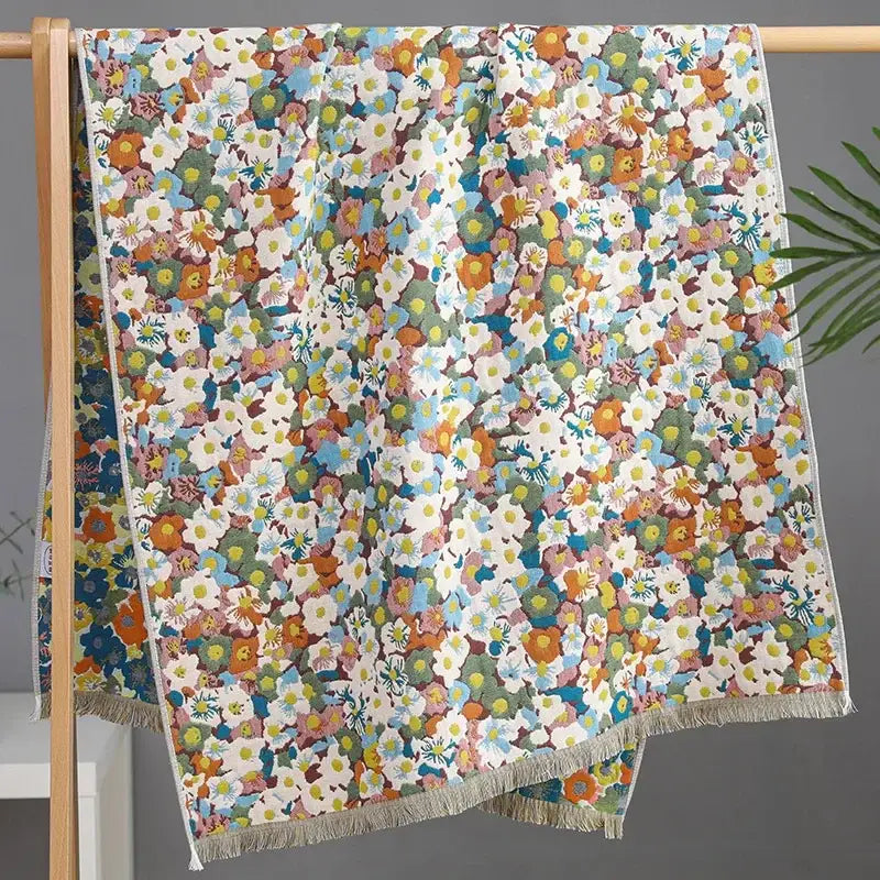 A country flowers cotton bath towel with a white base, vibrant orange blue green floral pattern, and frayed fringe decor