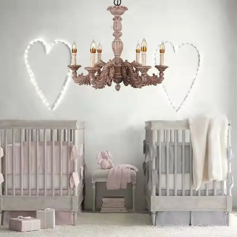 A delicate rose-gold country french solid wood chandelier with six candle-style bulbs above matching gray cribs