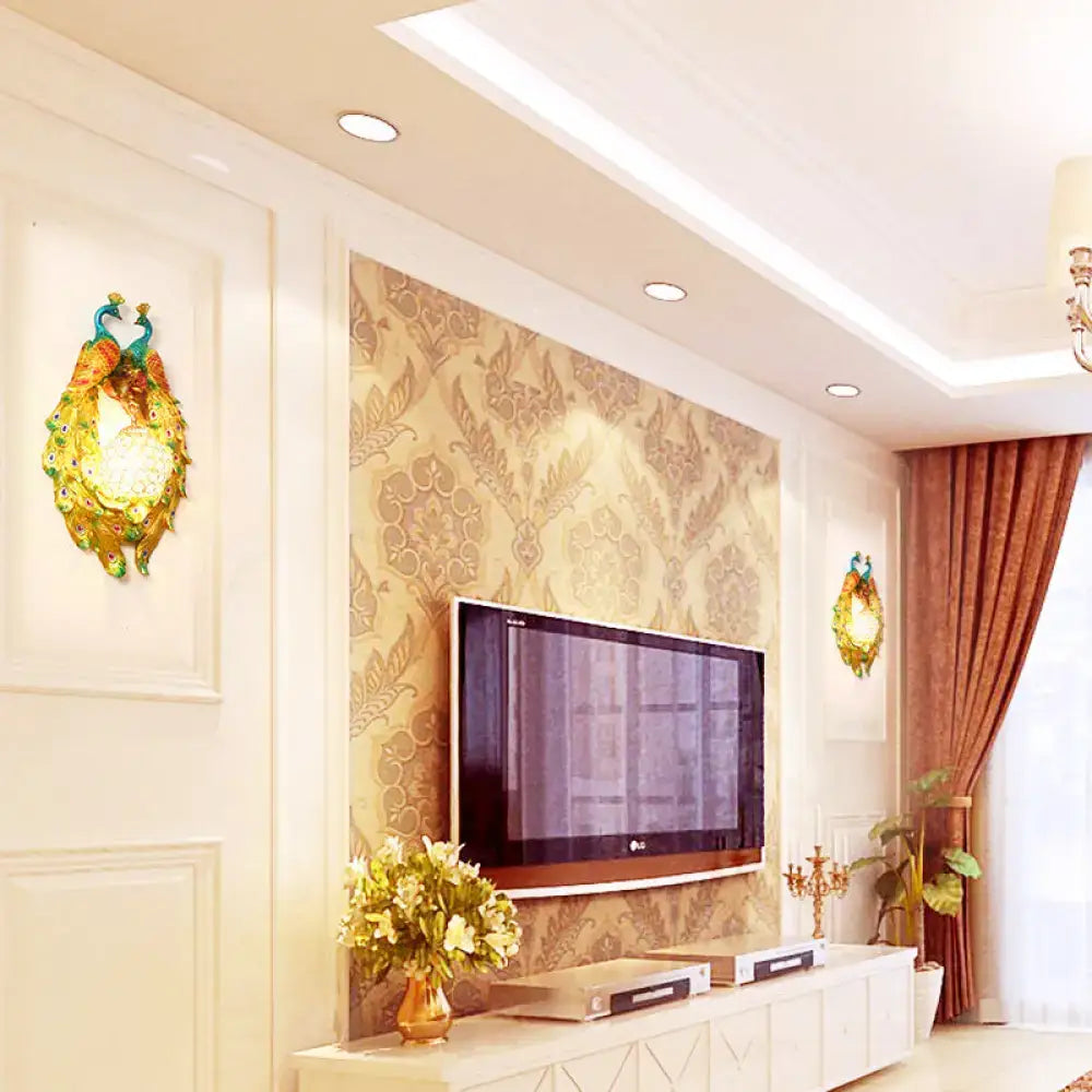 Gold-colored peacock wall sconce with intricate feather detailing and glowing central crystal light for bedroom use