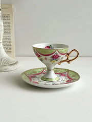 A delicate court style latte porcelain cup set with gold handle and pink green floral design on matching saucer