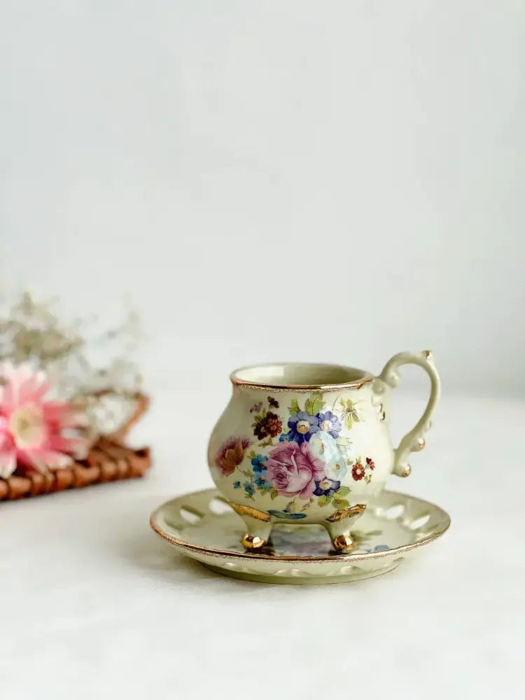 A delicate cream porcelain cup set with intricate floral patterns and gold handle from decorbites court style dining room