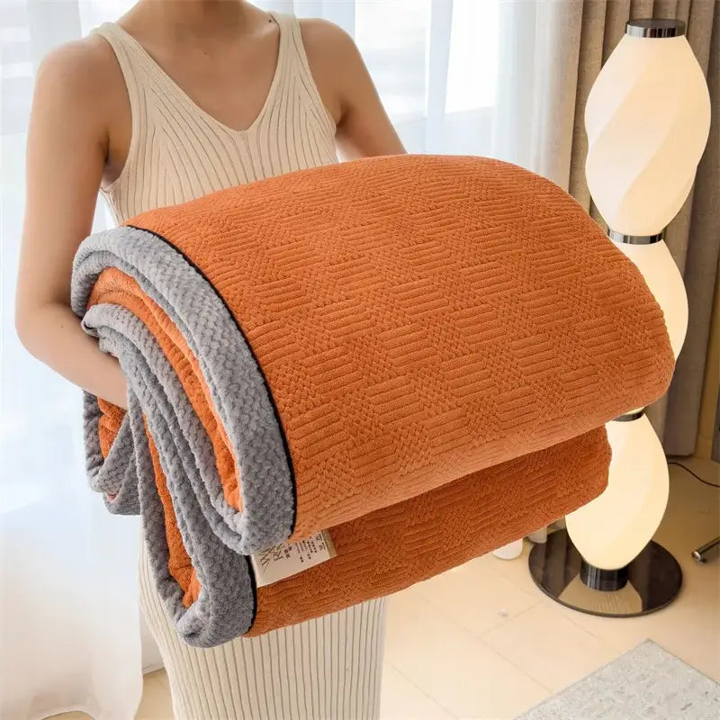 A cozy carved velvet cream and gray quilted bedroom throw featuring an orange and gray fleece textured weave blanket