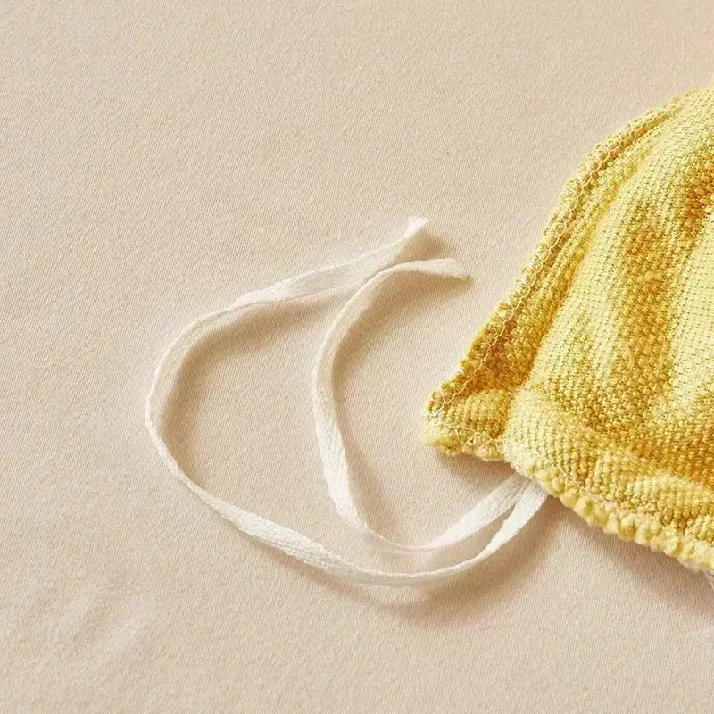Yellow knitted headband with white elastic strap displayed alongside cozy cashmere blanket duvet cover in yellow and white fleece