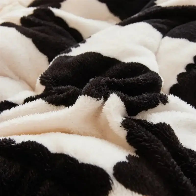A plush black and white cow-print winter blanket with soft fluffy texture from decorbites cozy checkerboard winter collection