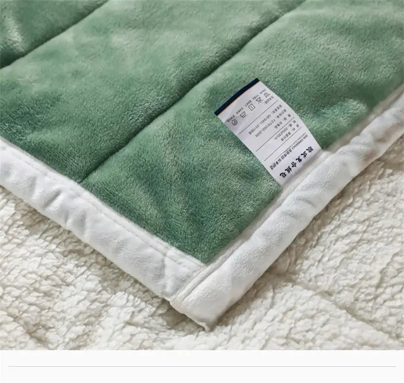 A cozy coral fleece blue and white quilted blanket featuring a soft green plush fleece with white sherpa border