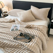 Cream-colored plush throw blanket with textured wavy ribbed pattern made of coral fleece for decorbites cozy coral fleece use