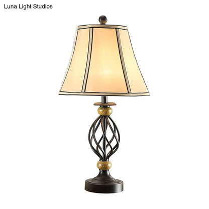 مصباح طاولة من القماش بتصميم ريفي دافئ مع قاعدة قفصية سوداء ملتوية - إضاءة ليلية مثالية لغرفة المعيشة