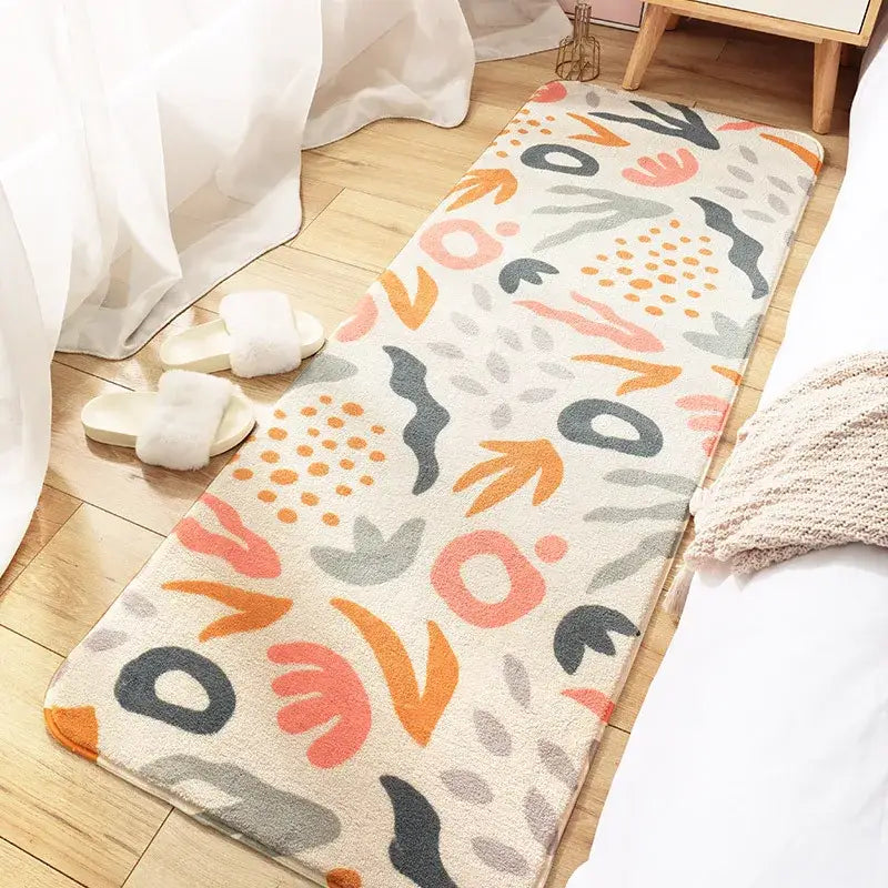 A cream-colored decorbites cozy faux lamb rectangular bedside rug with coral, orange, gray, and black abstract pattern