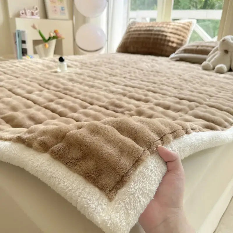 A cozy faux rabbit fur beige and cream quilted mattress pad with a plush, soft textured surface for decorbites cozy faux decor
