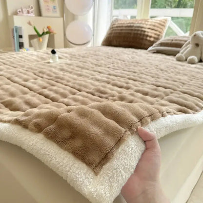 A cozy faux rabbit fur beige and cream quilted mattress pad with a plush, soft textured surface for decorbites cozy faux decor