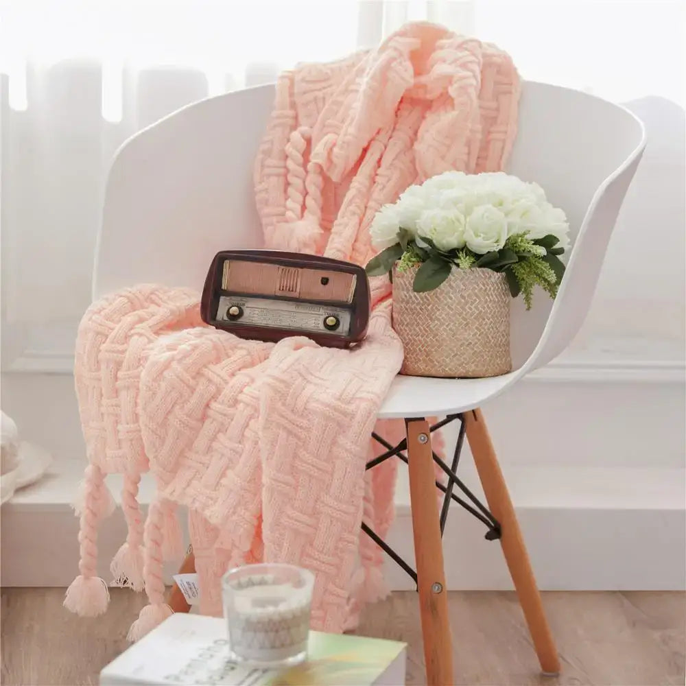 Soft peach-colored cozy fringed plaid knit throw blanket with tassels draped over white chair for bedroom decorbites cozy fringed