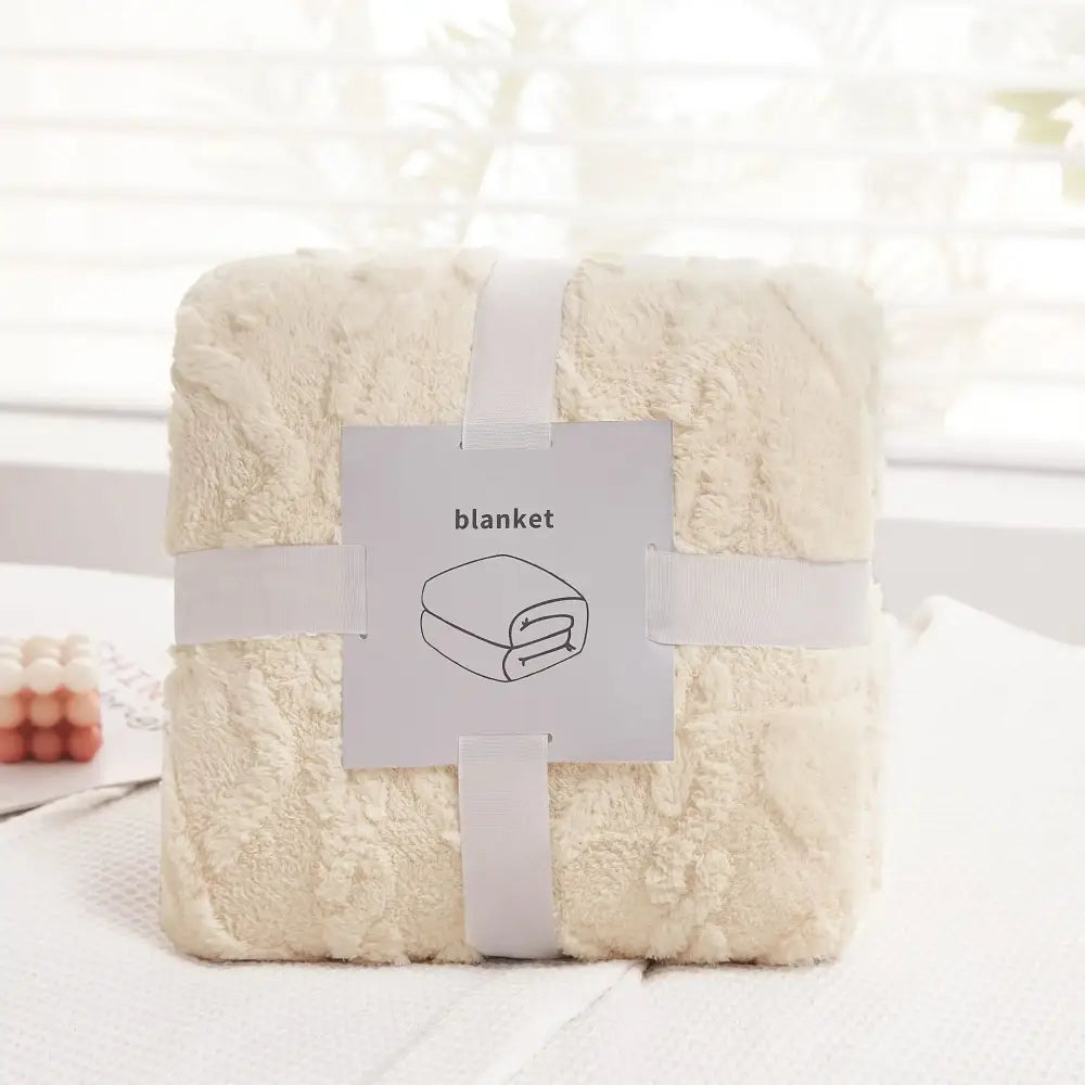 A cream-colored plush blanket made of cozy jacquard plush fleece neatly wrapped with a white ribbon for living room decor