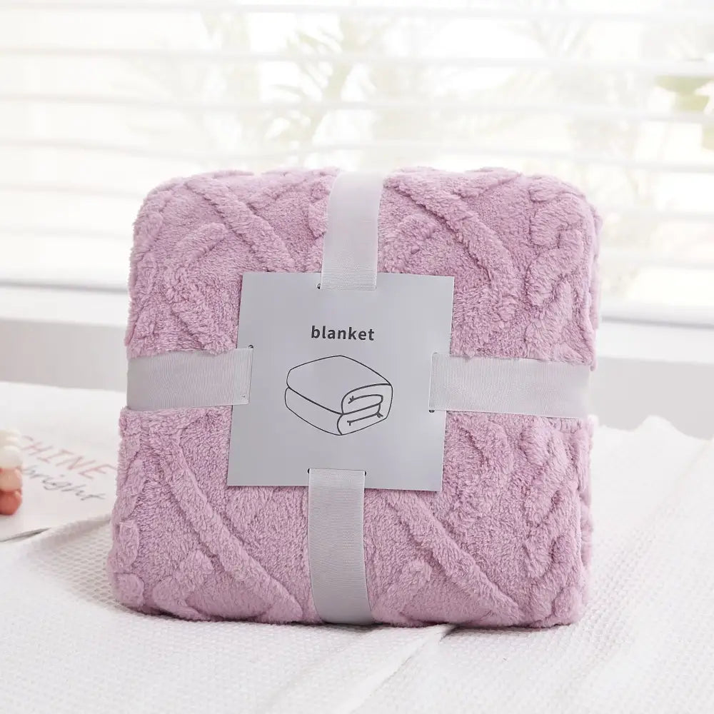 A soft plush blanket in lavender with a textured knit pattern wrapped with gray ribbons decorbites cozy jacquard plush