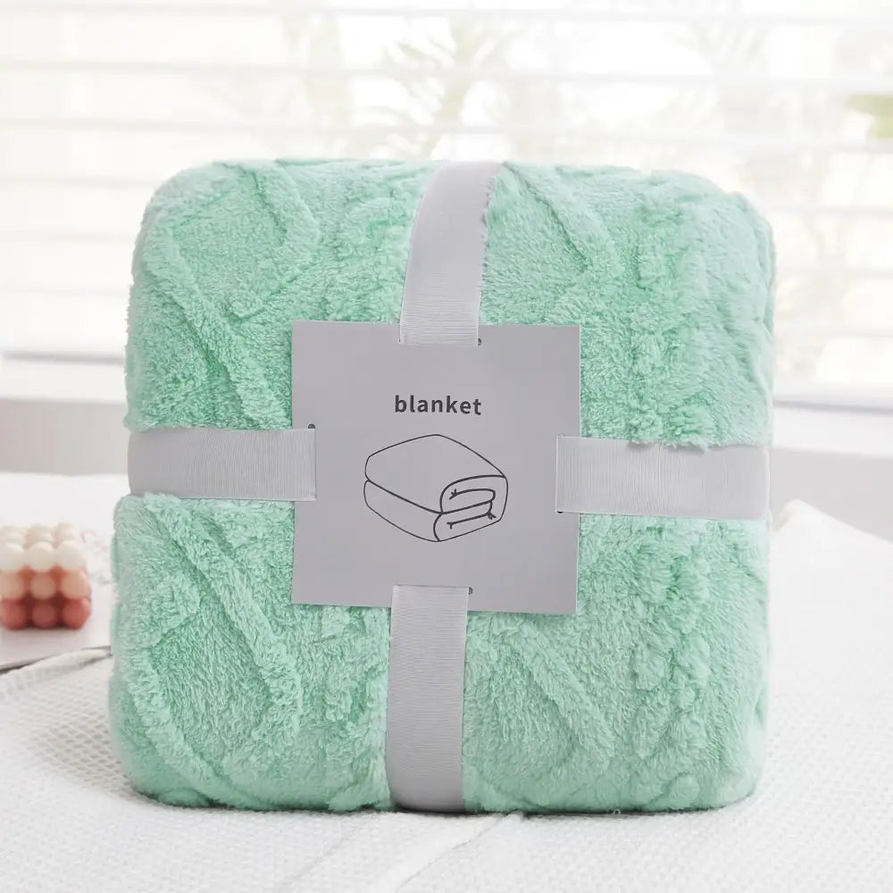 A soft mint green plush blanket with a textured looped surface neatly wrapped in white ribbon from decorbites cozy jacquard