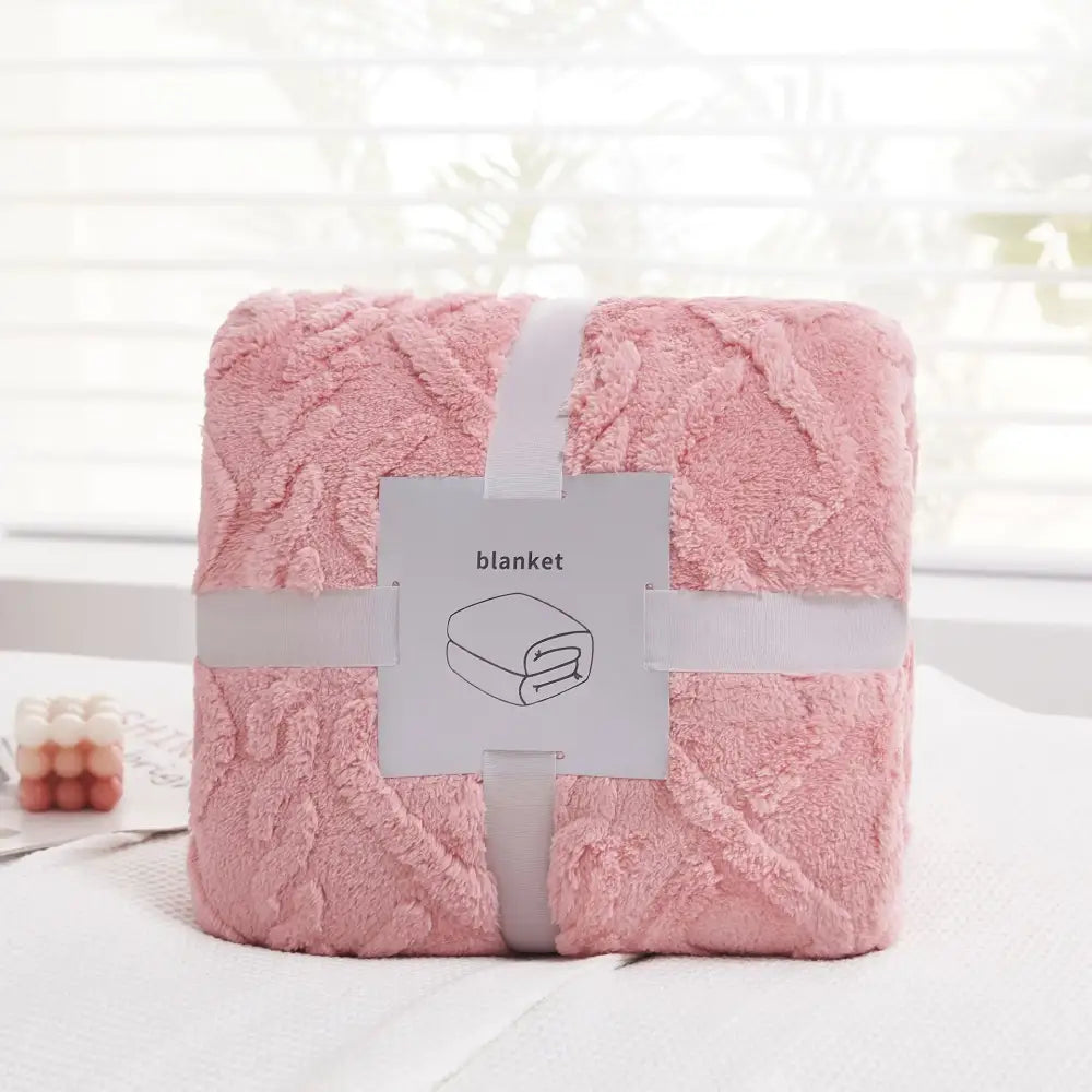 A soft pink plush blanket with a textured looped surface neatly wrapped in white ribbon from decorbites cozy jacquard