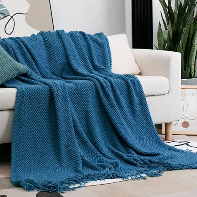 Cozy knitted sofa blanket in teal with textured weave and fringed edges draped over white sofa decorbites cozy knitted throw