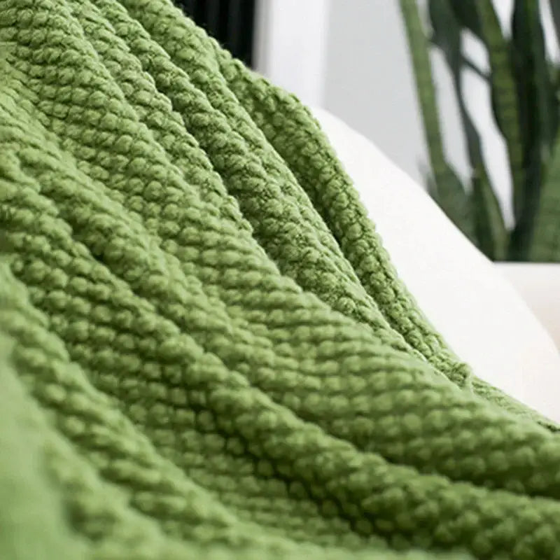 A moss green chunky knit sofa blanket with plush texture and tassels for cozy knitted decorbites living room use
