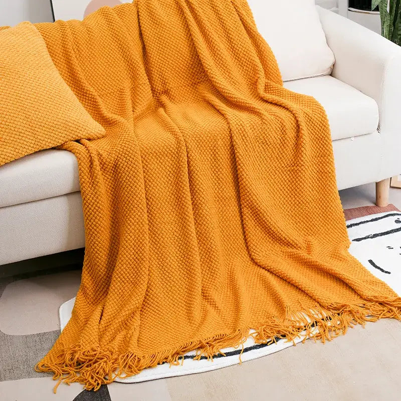 Mustard-yellow cozy knitted sofa blanket with textured weave and fringed edges from decorbites cozy knitted collection