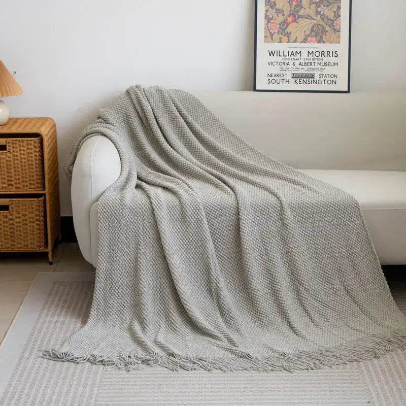 A soft light gray decorbites cozy knitted sofa blanket with textured weave and fringed edges for living room decor