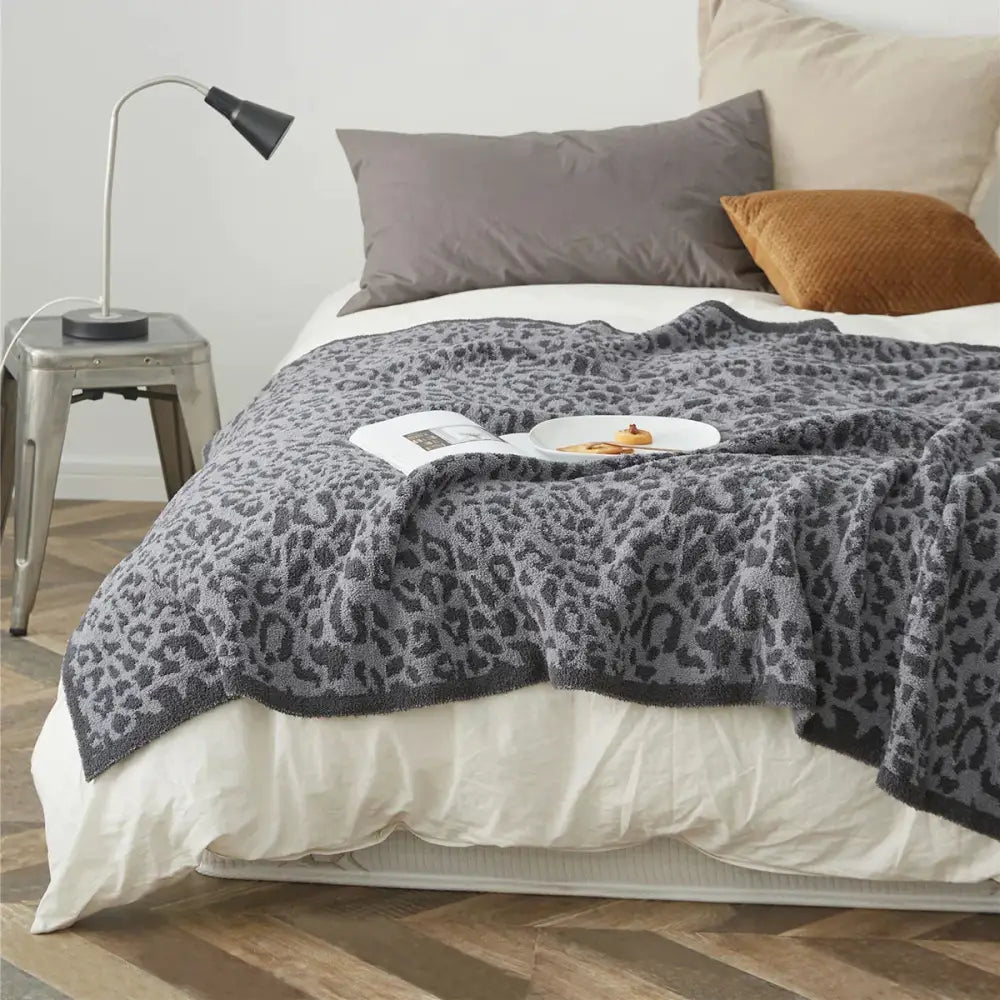 A cozy leopard print knitted gray and cream throw blanket with a soft textured surface for decorbites cozy leopard decor