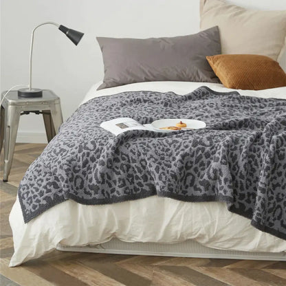 A cozy leopard print knitted gray and cream throw blanket with a soft textured surface for decorbites cozy leopard decor