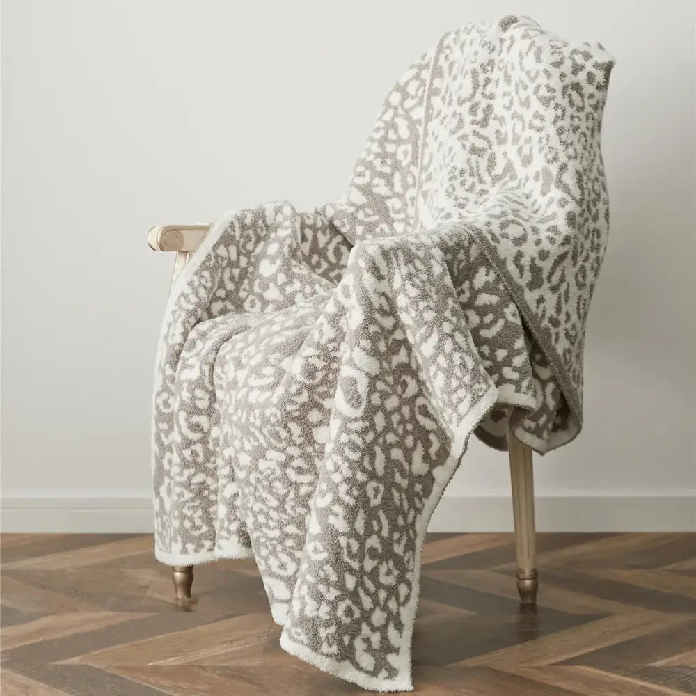 A plush cream and gray leopard print knitted throw blanket with a soft textured surface perfect for cozy leopard decorbites