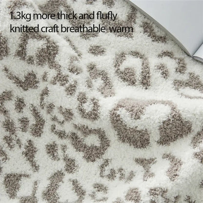 A plush cozy leopard print knitted cream and gray throw blanket with a soft white and beige leopard print pattern