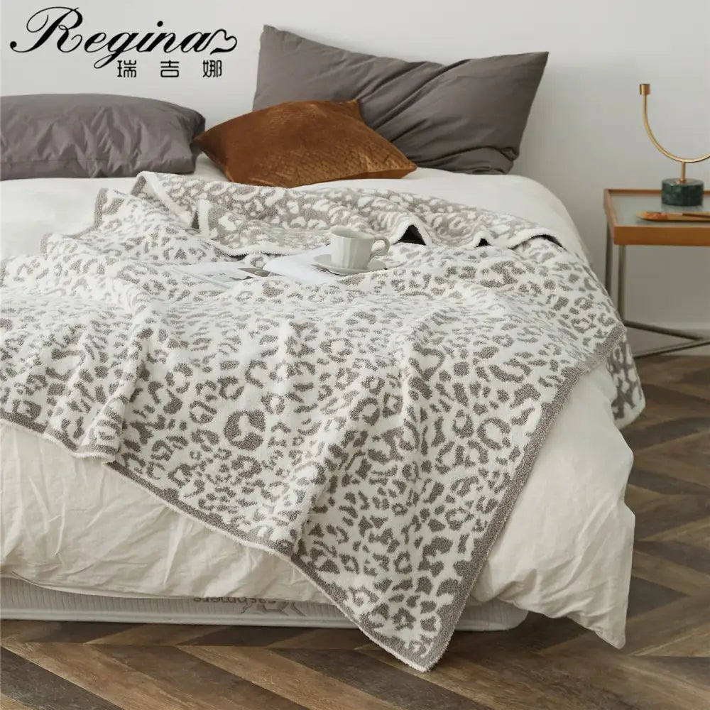 A cozy leopard print knitted cream and gray bedroom throw blanket with textured edges by decorbites cozy leopard