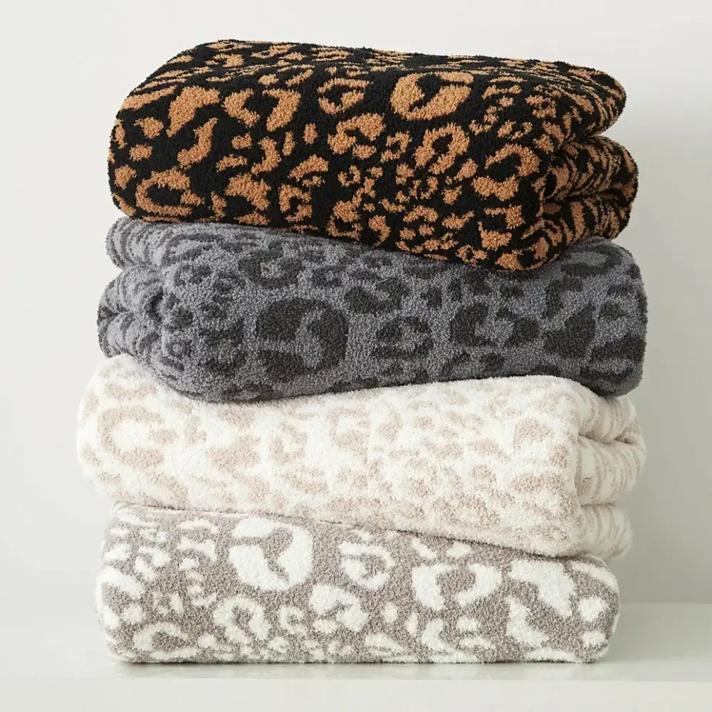 Stack of four plush leopard print knitted towels in black tan gray and beige complement decorbites cozy leopard throw