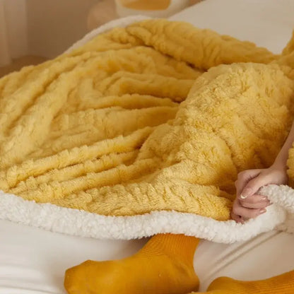 A cozy mustard coral fleece blanket with soft white sherpa lining for warmth and comfort in the bedroom