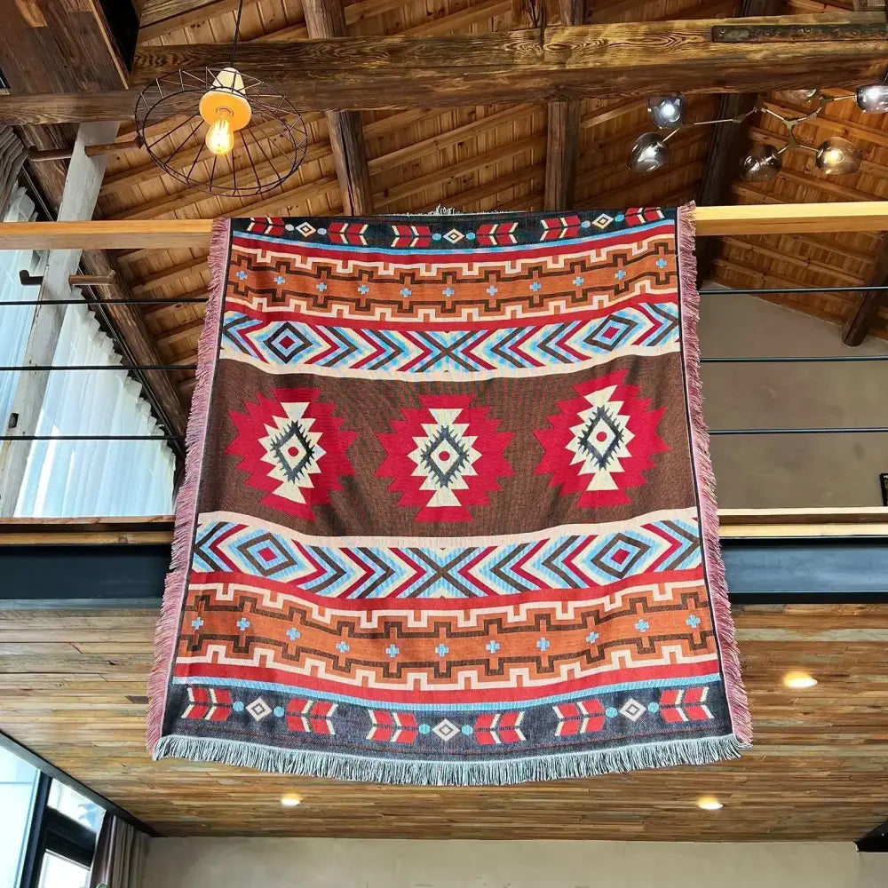 A cozy nordic camping blanket featuring a rectangular woven tapestry with bold red brown orange and blue geometric decorbites cozy nordic