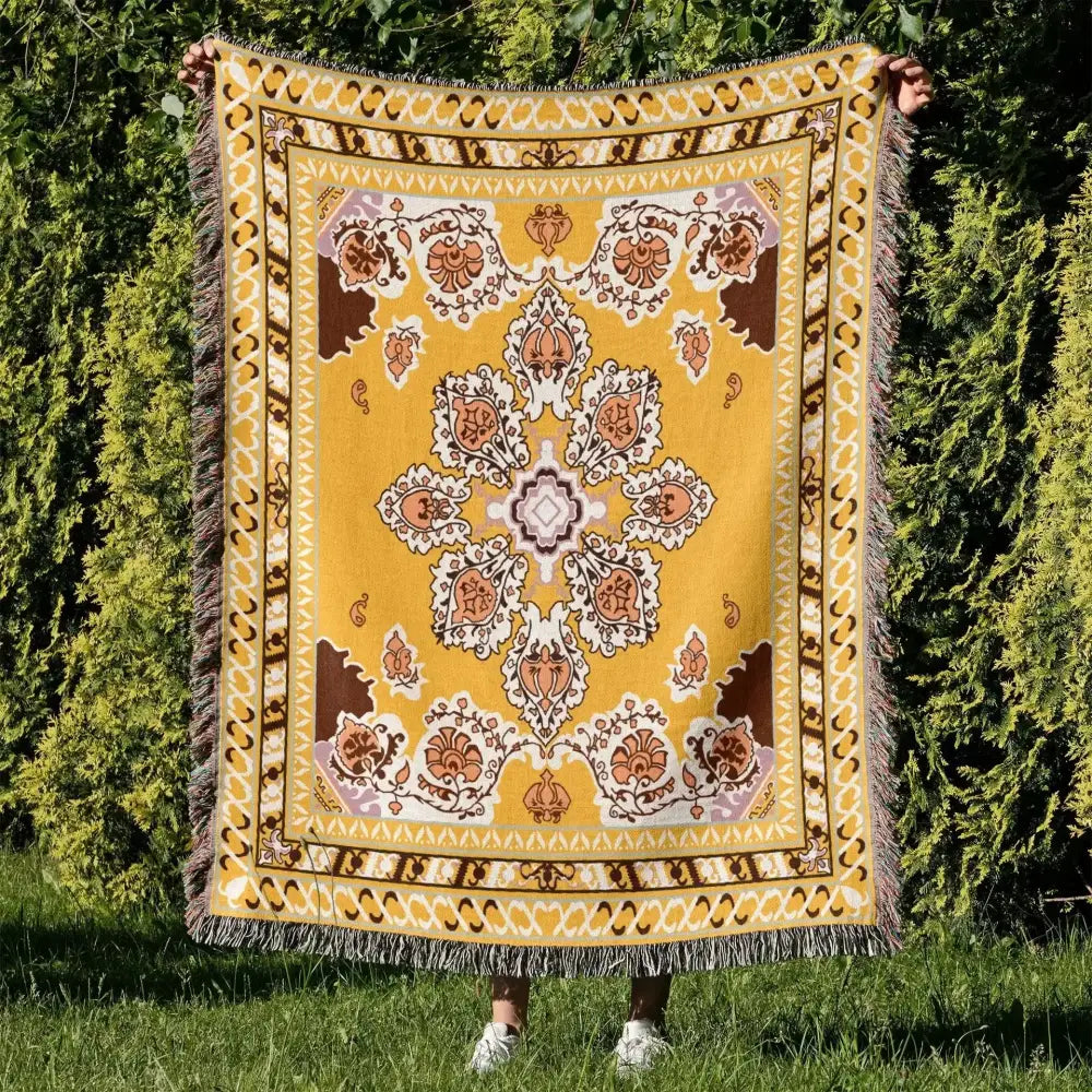 A mustard-yellow cozy nordic camping blanket with intricate floral geometric pattern and fringe for living room decor