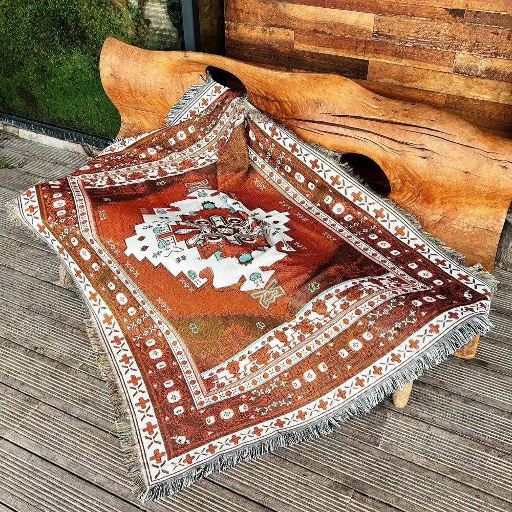 A cozy nordic camping blanket in orange and cream with intricate geometric patterns and fringed edges for living room decor