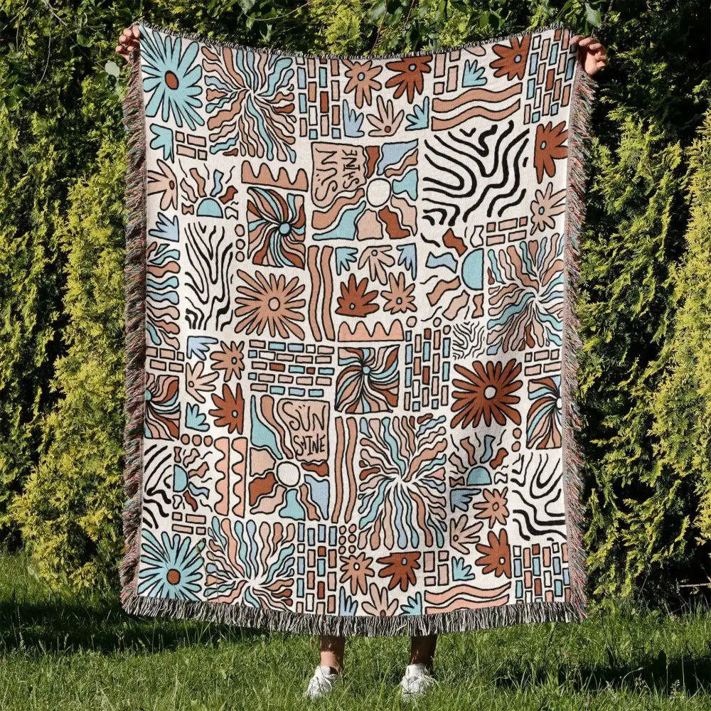 A cream-colored decorbites cozy nordic camping blanket with vibrant abstract floral and geometric woven pattern for living room decor