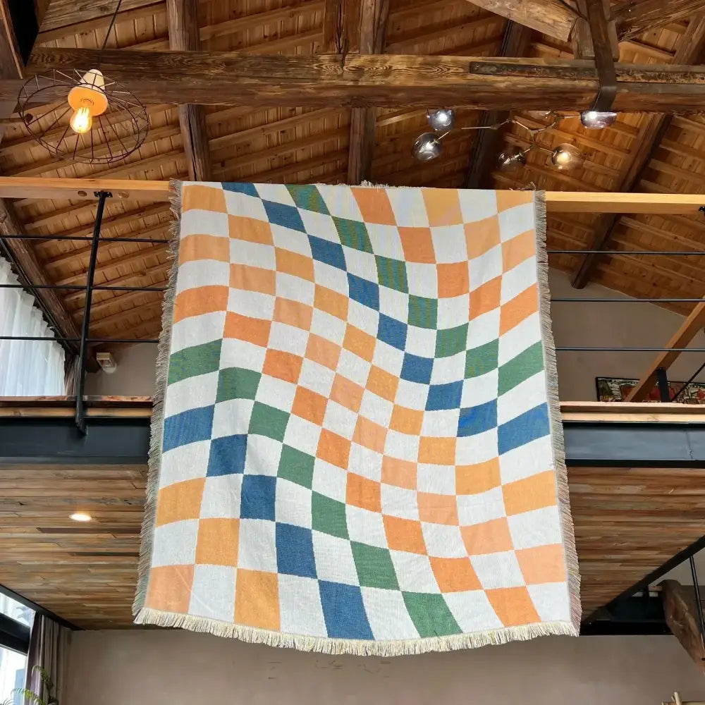 Cozy nordic camping blanket with vibrant orange blue green wavy checkerboard pattern and soft fringed edges for decorbites cozy nordic living room decor