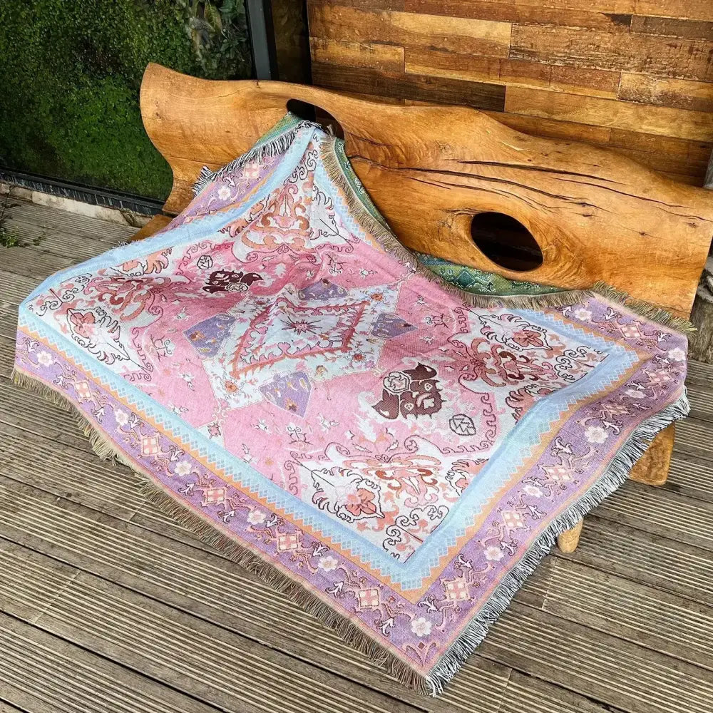 A cozy nordic camping blanket with soft pink and lavender floral patterns, fringed edges, and a light blue border