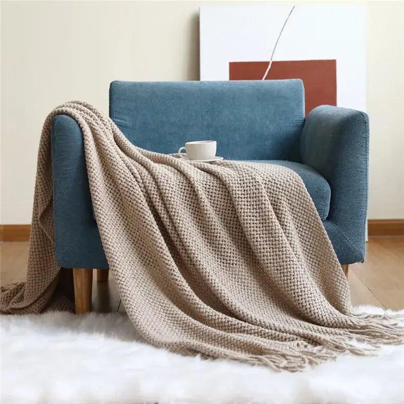 Beige cozy nordic knit textured tassel throw blanket draped over blue armchair for nordic knit sofa decorbites cozy nordic