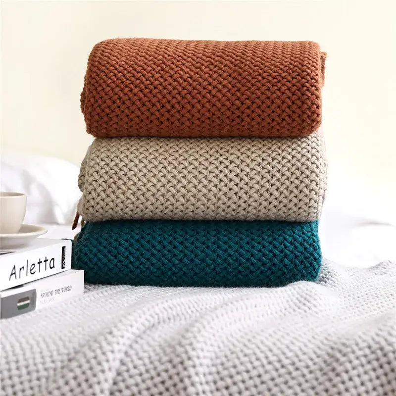 Stack of three cozy nordic knit sweaters in terracotta beige and teal with textured weave for nordic knit sofa decorbites