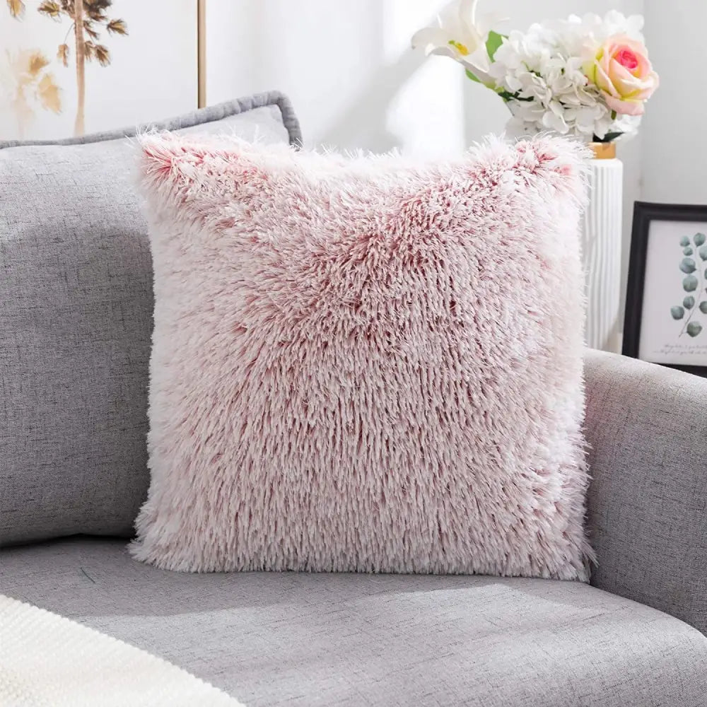 A soft pink cozy plush fur cushion cover with shaggy texture on a gray couch for decorbites cozy plush decor