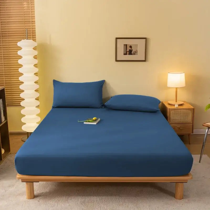 Blue cozy solid color fitted sheet with matching pillows made of smooth stretchy fabric snugly fitting mattress